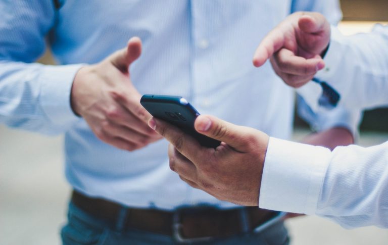 Mann zeigt anderem Mann etwas auf dem Bildschirm eines Smartphones